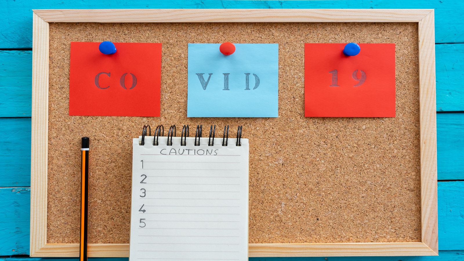 A neatly stacked set of question cards pinned to a corkboard beside a small calculator, lit by warm desk light